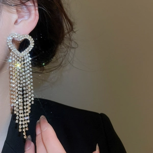 Close-up of heart-shaped zircon stud earrings with long sparkling crystal tassels