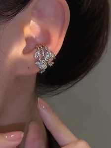 Macro view of silver triple-layer ear cuff with zircons worn on ear cartilage