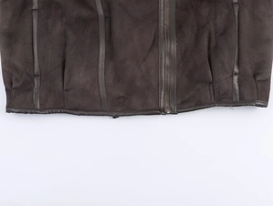 Detailed view of dark brown suede jacket hem with smooth leather trim and metal zipper