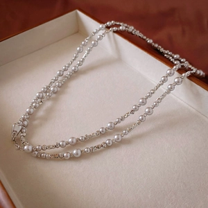 Detail of grey pearl double-layer necklace with textured beads and heart clasp in jewelry box