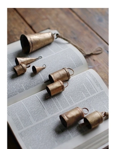 Vintage bronze metal bells in various sizes scattered on old book for Christmas decor