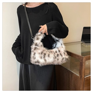 Model showing plush crescent handbag with faux fur leopard pattern and leather strap