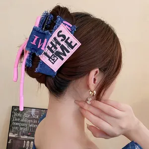 Denim bow hair claw clip with pink 'THIS IS ME' lettering on dark blue fabric