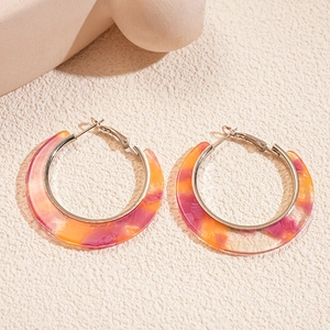 Detail of artistic colorful acetate C-shaped hoop earrings with silver pins on a texture surface