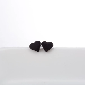 Minimalist matte black stainless steel heart stud earrings displayed on a white plate
