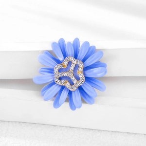 Close-up of blue daisy brooch with matte petals and sparkling crystal center details