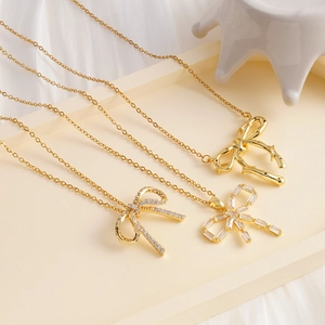 Elegant gold bow pendant necklace set with cubic zirconia on white silk background