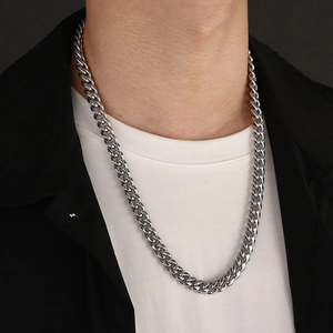 Close-up of a silver stainless steel Cuban link chain necklace worn by a male model
