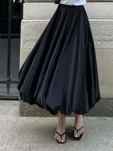Detailopname van zwarte high-waisted bubble rok met zijdeglans en volumineuze A-lijn snit
