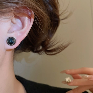 Close-up of vintage dark blue round zircon stud earrings on model for elegant styling