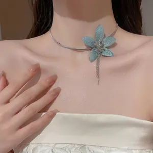 Blue fabric flower tassel necklace on a silver snake chain worn by a model