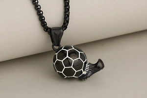 Macro shot of black soccer ball and football shoe pendant on a sports necklace