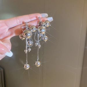 Macro detail of glossy silver ball fringe earrings featuring a starburst light effect