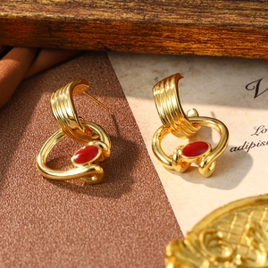 Detail view of gold-plated twisted loop earrings with red enamel on vintage paper
