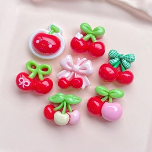 Close-up of colorful resin cherry charms in red and pink on a soft pink background
