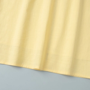 Détail du tissu en coton et lin jaune pâle avec des finitions à double couture uniforme