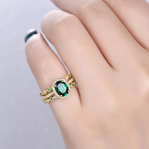 Detailed close-up of a vintage gold ring set with an oval green gemstone and white diamonds