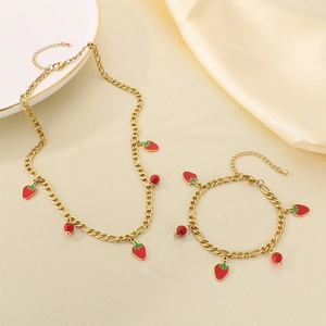 Close-up of 18K gold plated Figaro chain necklace and bracelet with strawberry charms