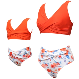 Flat lay of mother and daughter matching two-piece swimsuits with red floral print