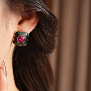 Detail of vintage square earring with green enamel and purple crystal on model ear