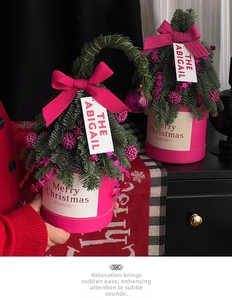 Close-up of mini Christmas tree in a pink cylindrical gift box with festive ornaments