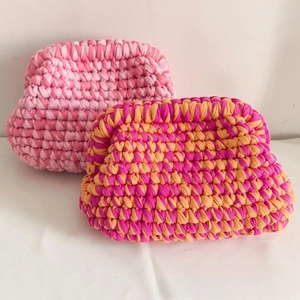 Detailed close-up of colorful handmade crochet cloud bags in pink and orange woven patterns