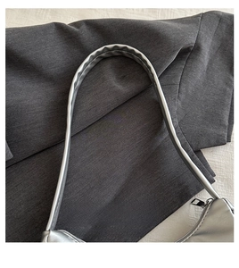 Detail shot of a sleek silver metallic handbag handle with high-quality stitching