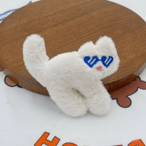 Close-up of white plush cat patch with blue heart-shaped sunglasses for DIY clothing
