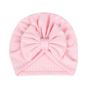 Detail of baby pink ribbed knit hat featuring a large decorative bow for newborns