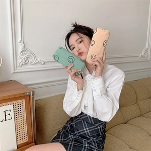 Detail of corduroy makeup bags with smiley faces in mint green and beige colors