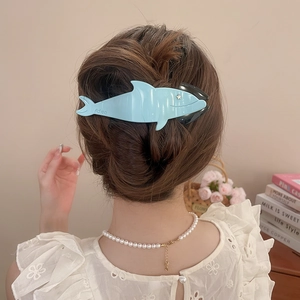 Close-up of blue acrylic shark hair claw clip with star detail on brown bun hair