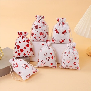 Off-white cotton gift bags with red heart patterns and drawstring for wedding favors