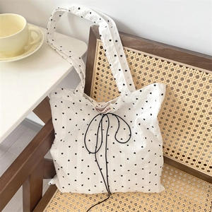 Detailed view of white canvas tote bag with black heart pattern on a wooden chair