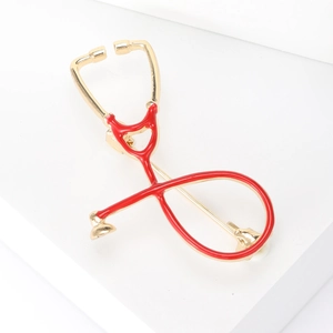 Detailed close-up of a gold metal and red enamel stethoscope brooch for medical staff
