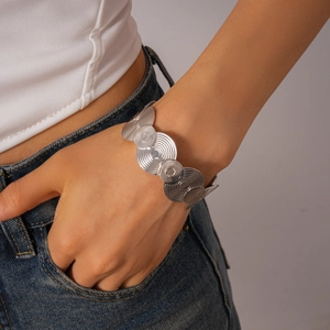 Close-up of silver metal geometric wavy disk bracelet on wrist with textured finish