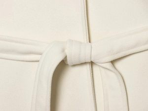 Detailed macro view of the soft white plush fabric texture and tied waist belt on coat