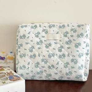 Detail of green floral quilted cotton makeup bag with a zipper and beige woven label