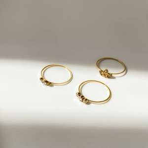 Detailed view of three minimalist 18K gold stackable rings with teardrop rhinestones