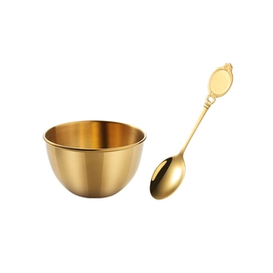 Polished golden stainless steel sauce bowl and decorative spoon set on white background