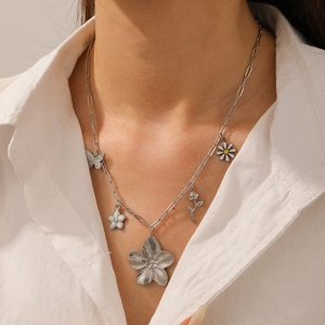 Detail of silver stainless steel necklace with oversized flower and butterfly charms