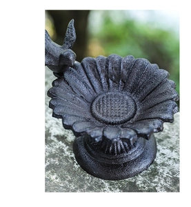 Detailed close-up of a cast iron sunflower bird feeder with a small bird sculpture