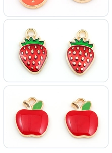 Macro shot of red strawberry and apple alloy pendants with gold trim for DIY jewelry