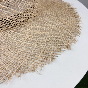 Detail of hand-woven straw hat showing fringe brim and rustic hollow knit pattern