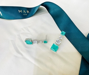 Detail of silver drop earrings with square emerald stones and white zircon accents