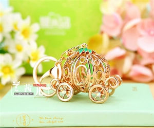 Close-up of golden pumpkin carriage keychain with white rhinestones and green enamel details