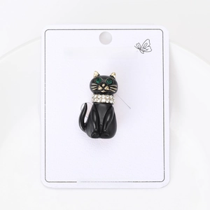 Detail shot of a black enamel cat brooch with green rhinestone eyes and gold metal accents