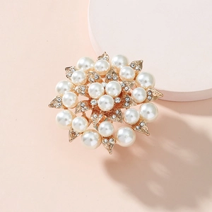 Elegant gold flower brooch with radiant pearls and sparkling rhinestones on pink podium