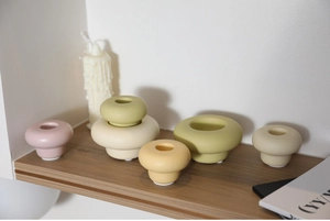 Artistic matte ceramic candle holders in Morandi colors on wooden shelf for home decor