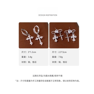 Detail view of silver cross earrings with heart zircon and safety pin design on leather