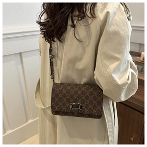 Detail of leopard print shoulder bag featuring metal buckle and chain strap on a model